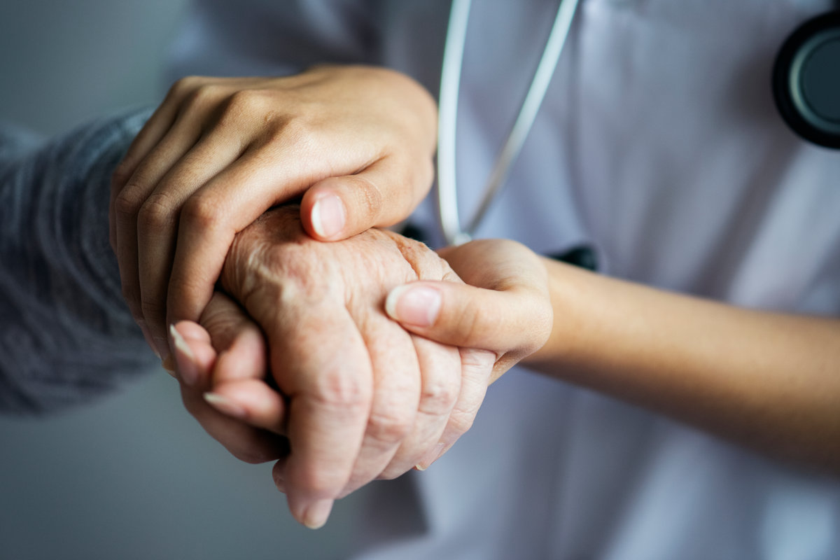 Soignante tenant la main d'une personne âgée