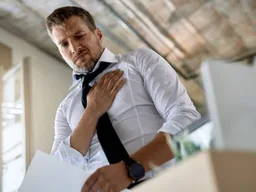Homme en chemise pris d'un malaise, la main sur la poitrine